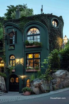 a green building with windows and plants on the top floor is lit up at night