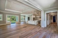 an empty living room with wood flooring and white trim on the ceiling is shown