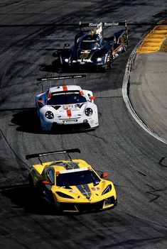 three race cars driving around a track