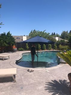 a person standing in the middle of a pool with an umbrella