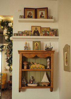 a shelf with pictures and figurines on it in the corner of a room