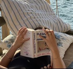 a woman reading a book while sitting on a boat