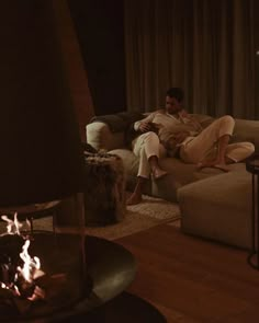 a man and woman sitting on a couch next to a fire place