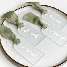 three pieces of glass with green ribbons on them sitting on a white plate that says home, family, and love