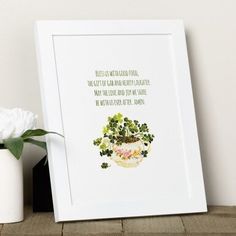 a white vase sitting next to a green plant on top of a wooden table with a quote written in it