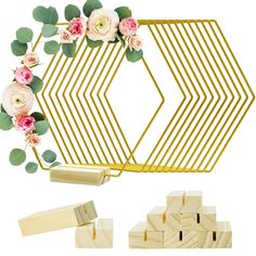 a wooden block with flowers and greenery on it next to a gold geometric frame