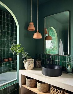 a bathroom with green tiles and hanging lights