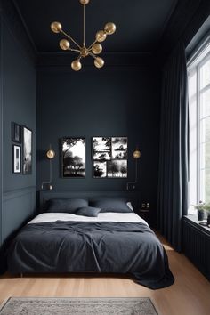 a bedroom with black walls and wooden floors, two pictures on the wall above the bed