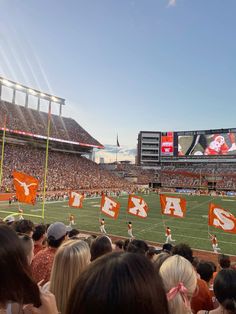 a football stadium filled with fans and players on the sidelines holding flags that read texas