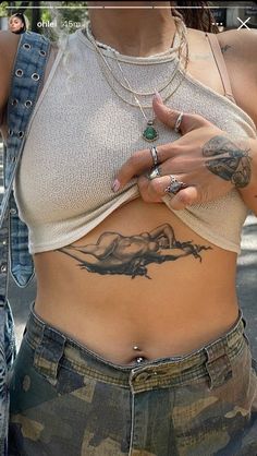 a woman with tattoos on her stomach holding a cell phone