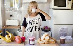 a woman standing in a kitchen drinking from a cup