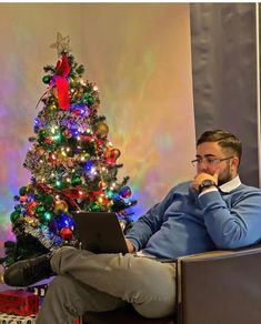 a man sitting in front of a christmas tree on his laptop