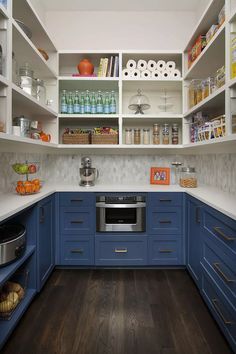 a kitchen with blue cabinets and white counter tops is pictured in this image, the shelves are full of food