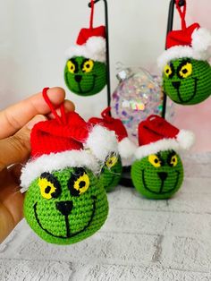 the grin face ornaments are being held up by someone's hand and they have santa hats on them