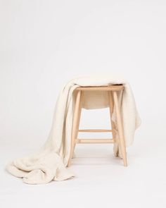 a wooden stool with a white blanket draped over it