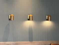 three lights are on the wall above a wooden bench in a room with blue walls