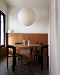 a dining room table with two chairs and a lamp hanging from the ceiling over it