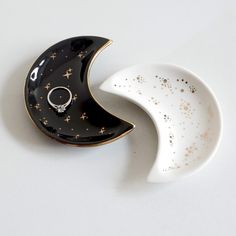 two black and white dishes with gold stars on them, one is shaped like the moon