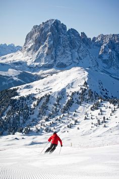 a man riding skis down the side of a snow covered slope next to a mountain