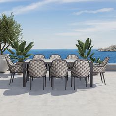 an outdoor dining table with chairs and potted plants next to the water's edge