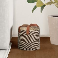 a basket sitting on top of a wooden floor next to a potted plant