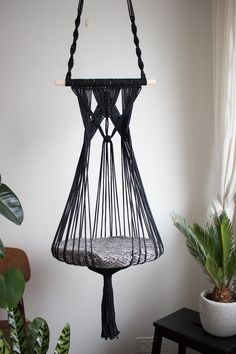 a black hanging chair next to a potted plant