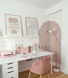 a white desk topped with a pink chair next to a wall mounted art work area