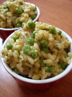 two bowls filled with rice and peas on top of a wooden table next to each other