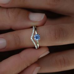 a woman's hand holding an engagement ring with a blue stone in it and diamonds around the band