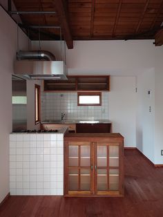 an empty kitchen with wooden floors and white tile walls, is pictured in this image