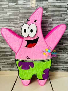 a paper cut out of a pink cartoon character with big eyes and green pants on the floor