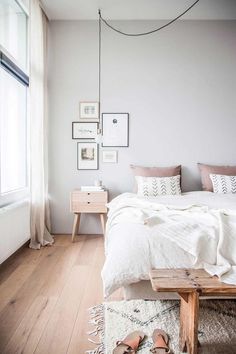 a bedroom with white walls and wooden flooring is pictured in this image, there are shoes on the bed