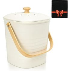 a white bucket with a wooden handle and a bow on the top is next to a black box