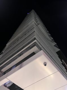 the top of a tall building with a clock on it's face at night