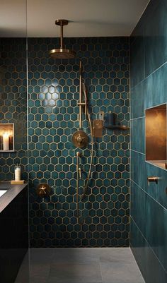 a bathroom with green tile and gold fixtures on the shower head, wall lights and mirror