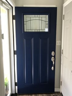 a blue front door with stained glass on the top and bottom panel, in an empty room