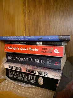 a stack of books sitting on top of a wooden shelf next to a glass vase