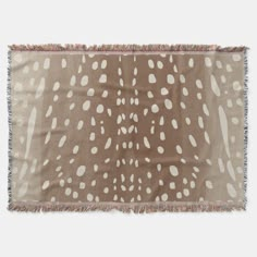 a brown and white spotted animal print throw blanket with fringes on the edges,