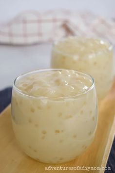 two glasses filled with food sitting on top of a wooden tray