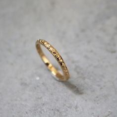 a gold wedding ring sitting on top of a cement floor