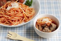 two bowls of spaghetti with meatballs and parmesan cheese on the side next to a fork