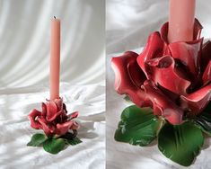 two candles that are sitting next to each other on a white sheet with leaves and flowers