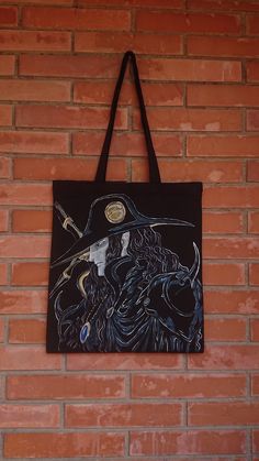 a black tote bag hanging on a brick wall with a drawing of a wizard