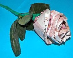 a rose that is sitting on top of some paper money and has been rolled up