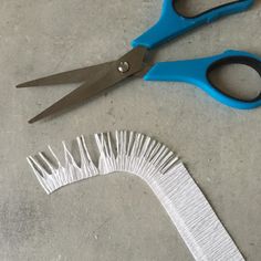 two pairs of scissors sitting next to each other on a table with white and blue strips