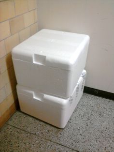 two white coolers sitting next to each other on the floor in front of a wall