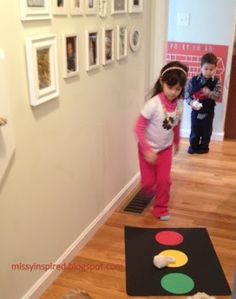 two children are playing on the floor in front of some pictures and magnets hanging on the wall