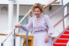 an older woman in a purple dress is standing on the steps of a cruise ship