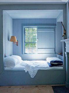 a small bed in a room with a window and lamp on the wall next to it