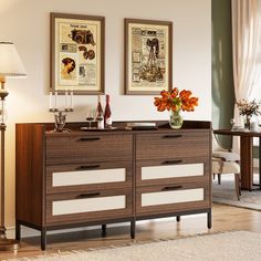 a living room with two pictures on the wall and a dresser in front of it